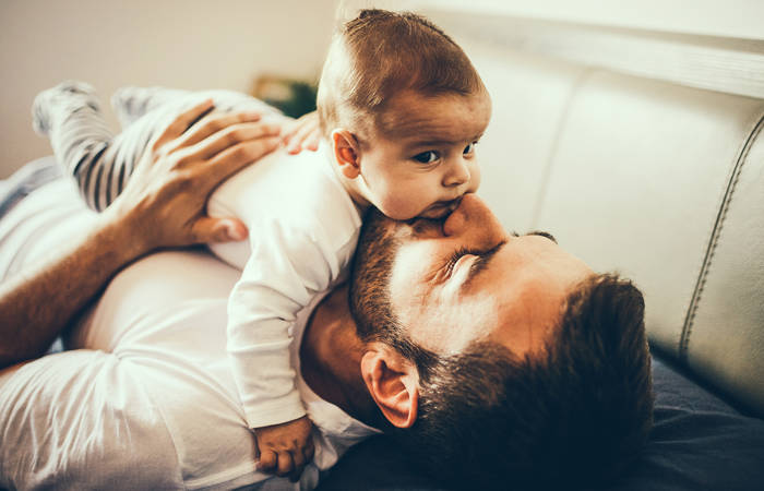 Father playing in bed with his little baby boy