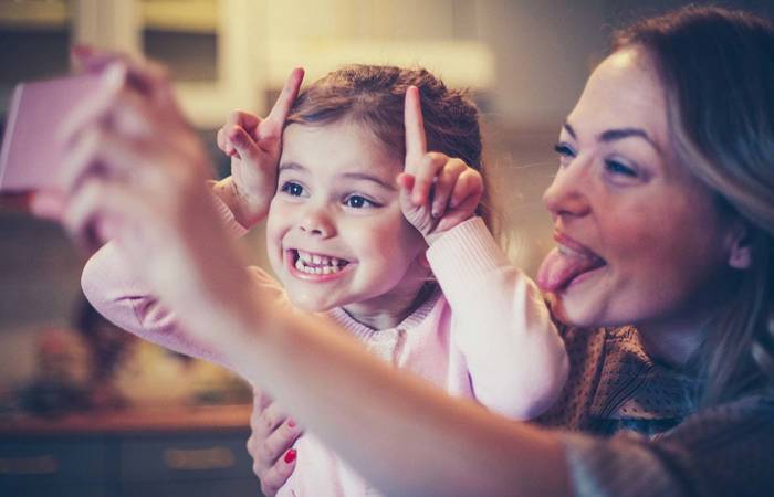 Mother and daughter photographing funny faces