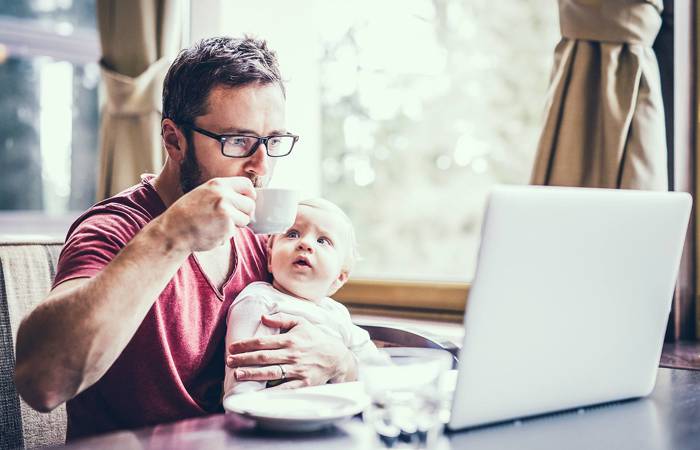 Man with notebook in cafe drinking coffee, holding his son