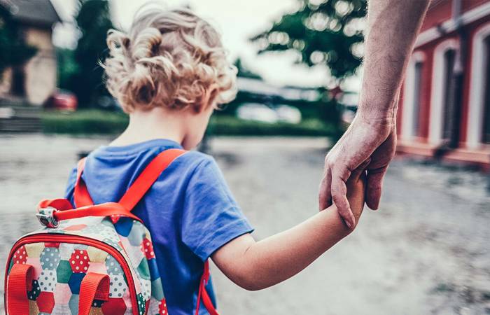 Small child with backpack holding parent's hand