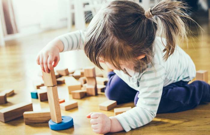 Girl building a tower of wooden blocks