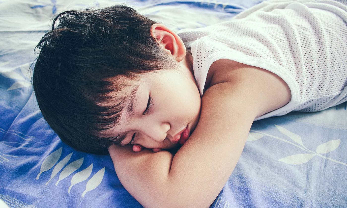 Boy sleeping in bed on blue blanket