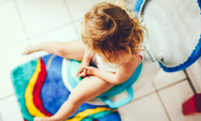 Baby girl child sitting on toilet with seat