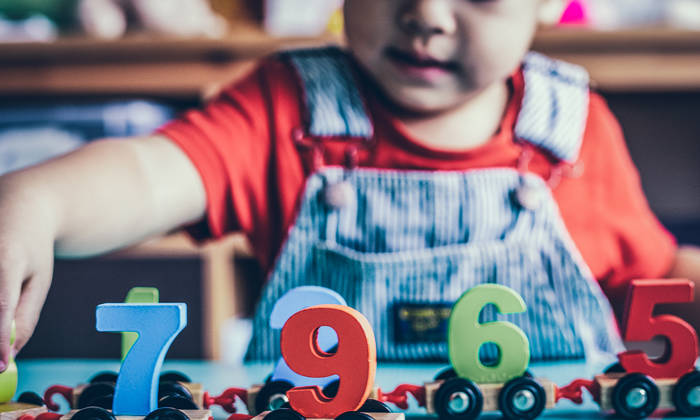 Little boy playing with a mathematics wooden toy
