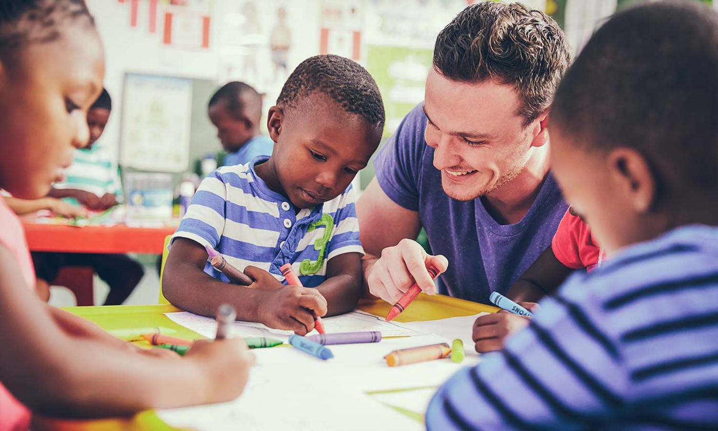 Teacher helping a class of preschool kids drawing