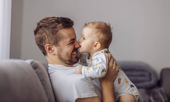 Boy playing with his father and biting his nose.