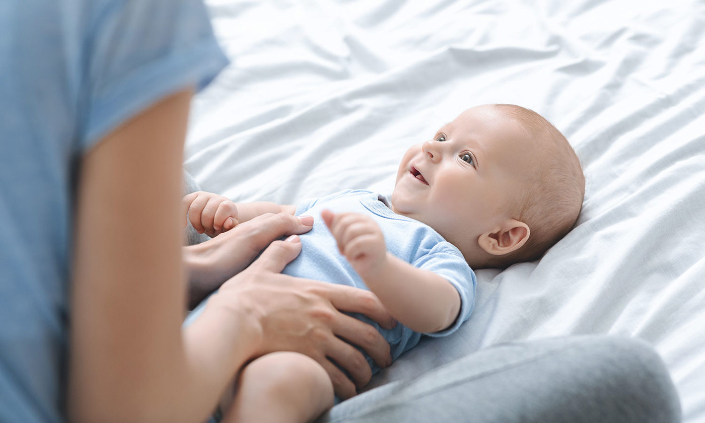 Mother massaging her newborn's son tummy