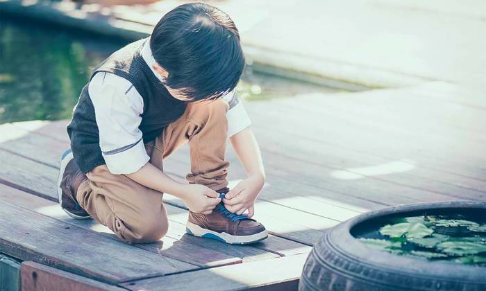 Boy trying to tie shoelace