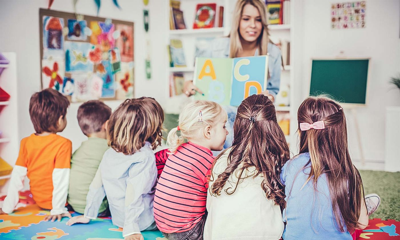 teacher reading a book to children in a classroom