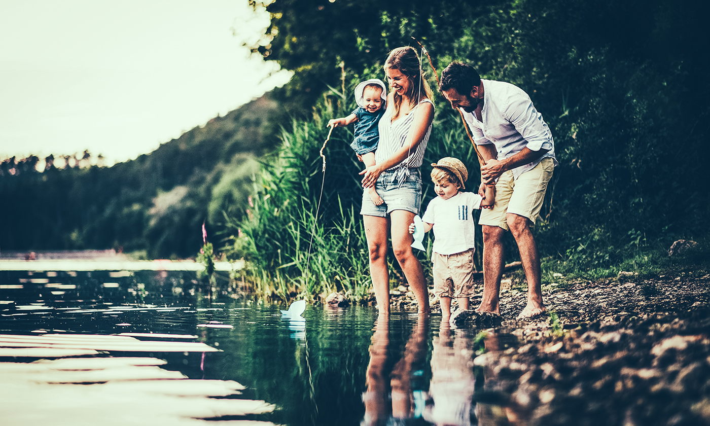 A young family with two toddler children outdoors by the river